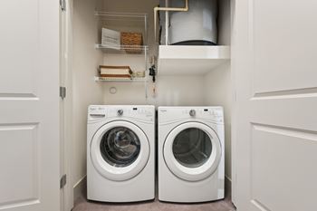 Two white front loading washing machines in a small laundry room.